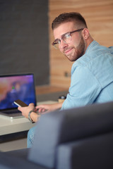 Young man using phone and works on the laptop.