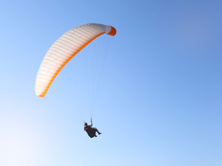 Man flying on a paraglider on the blue sky background