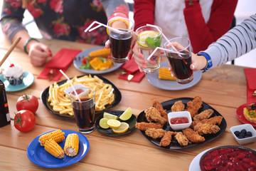 Top view of group of people having dinner together while sitting at wooden table. Food on the table. People eat fast food.