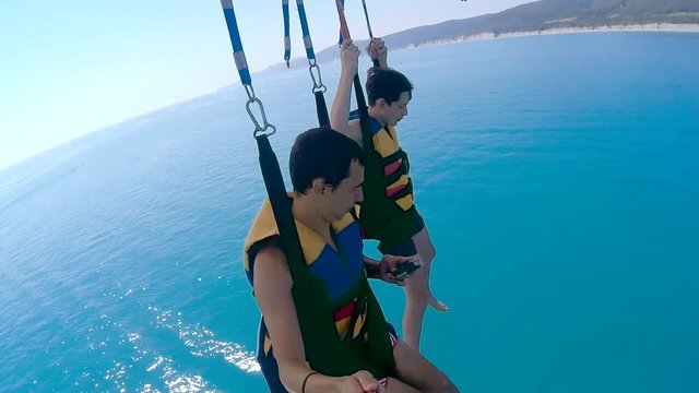 paragliding and parasailing lifestyle. man and boy are flying on a parachute over ocean the sea. Extreme sport first-person view