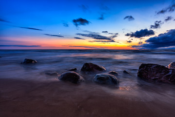 Fototapeta na wymiar Baltic Sea sunset seascape with wet rocks. Smooth long exposure of waves