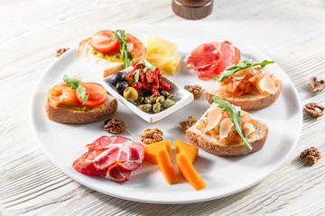 Selection of tasty bruschetta or canapes on taosted baguette and quark cheese topped with smoked salmon, shrimp.