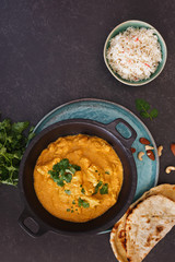 Chicken Korma, traditional Indian dish with nuts, jeera rice and naan bread on rustic surface. Top view, blank space