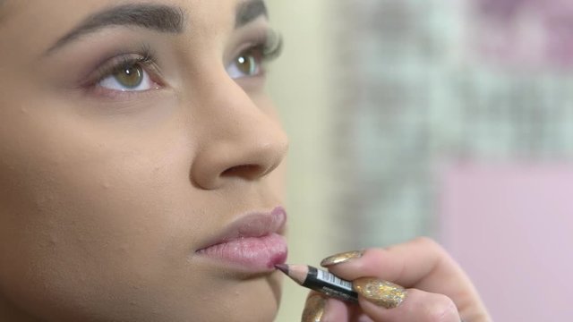Hands using lip pencil. Makeup close up. Professional cosmetics advertising.