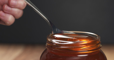 spoon in glass jar full of honey