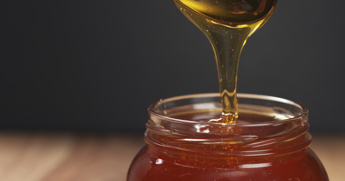 Honey Pour With Spoon In Glass Jar