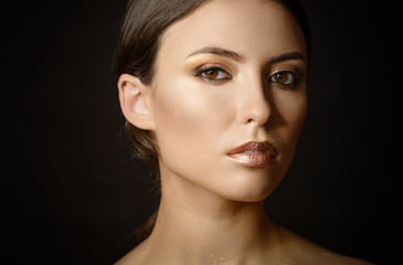 Fototapeta premium Close-up portrait of young woman with golden makeup.
