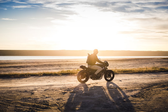 Motorcyclist driving his motorbike on the road during sunset