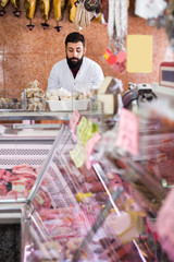 Assistant arranging meat to sell in butcher’s store