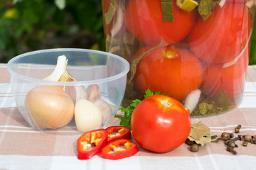 Plastic barrel with salted tomatoes. Products for the recipe. Pepper, onion, garlic, spices. Against the backdrop of a village tablecloth.