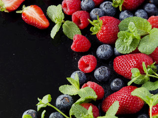 ripe red raspberries and strawberries in wooden bowl, selective focus