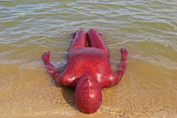 beautiful curvy woman wearing red spandex fetish zentai costume on the beach