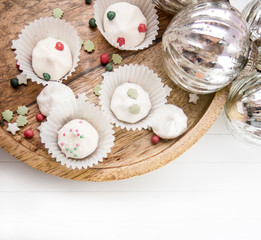 Holzteller mit weihnachtlicher Zuckerdekoration, Baiser und Glaskugeln