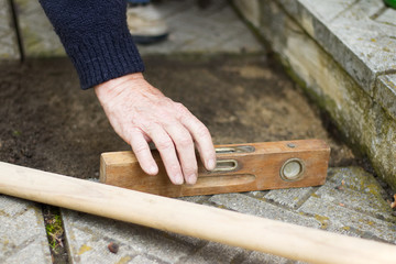 Repair of the tile pavement. Installation of paving slabs. Man controls the level with the spirit level. 