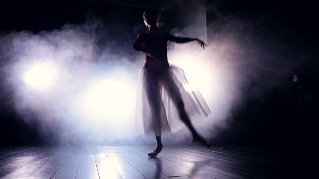 A ballet dancer jumps in the dark. 