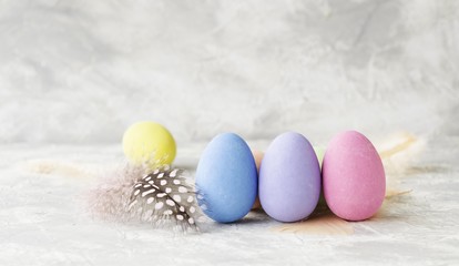 colored Easter eggs with feathers on a marble white table, selective focus