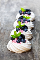 Mini  Pavlova meringue nests with berries and thyme on rustic wooden table