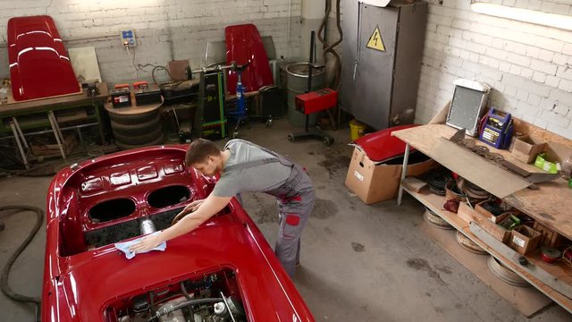 Mechanic polishning car in restoration workshop