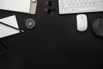 Office desk table of Business workplace and business objects of keyboard,mouse,white paper,notebook,pencil,compass and magnifying glass on black background.