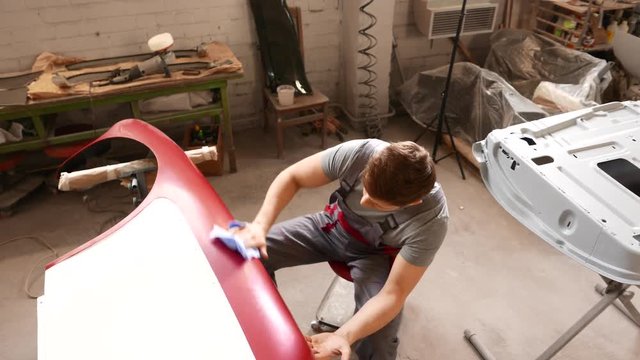 Mechanic polishning car body details in restoration workshop