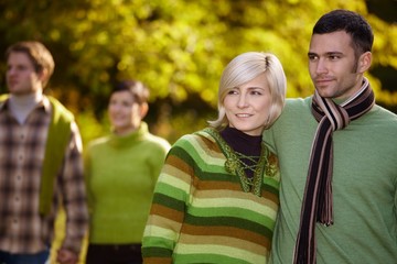 Happy casual couple with friends walking outdoor