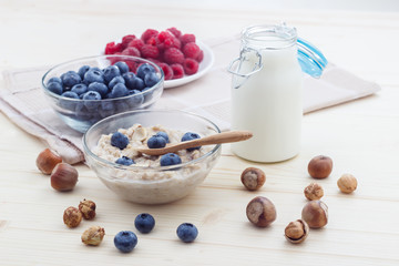 Breakfast of oatmeal with blueberries, raspberries, honey, milk and hazelnuts