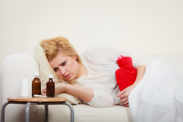 Obraz na płótnie Canvas Woman feeling stomach cramps lying on cofa