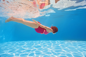 Pregnant woman swim, dive, pose underwater in swimming pool with red fabric. Aqua fitness healthcare classes for pregnancy. Aquatic therapy workout is one of safest, most efficient forms of exercises