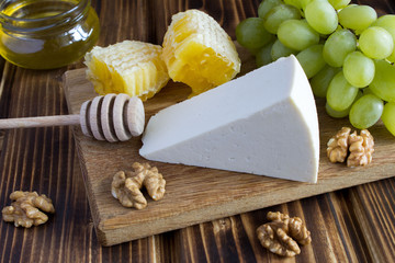 Cheese, honey and grapes on the brown cutting board