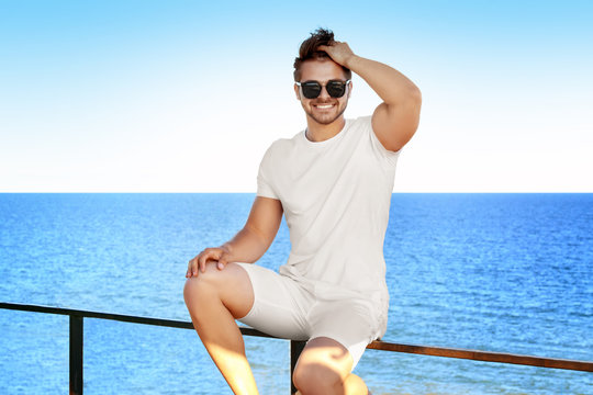 Handsome young man against sea on sunny day