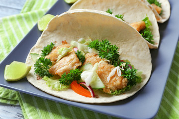 Plate with tasty fish tacos on table