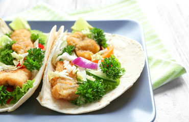 Plate with tasty fish tacos on table