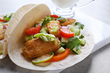 Marble board with tasty fish tacos on table
