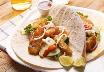 Plate with tasty fish tacos on wooden table