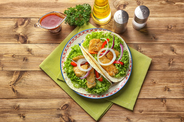 Plate with tasty fish tacos on wooden table