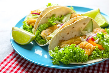 Plate with tasty fish tacos on table