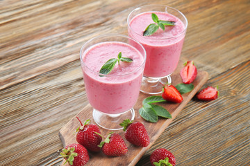 Glasses of fresh strawberry smoothie on wooden table