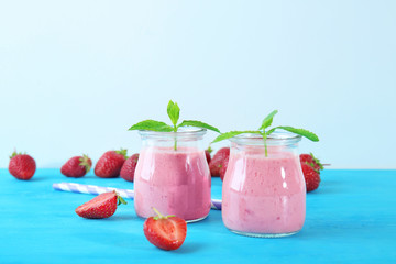 Fresh strawberry smoothie in jars on wooden table