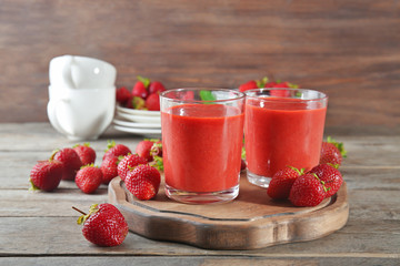 Glasses of fresh strawberry smoothie on wooden table