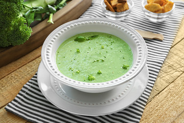 Plate with delicious broccoli cheese soup on wooden table