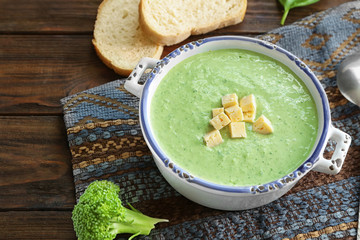 Plate with delicious broccoli cheese soup and croutons on wooden table