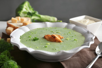 Plate with delicious broccoli cheese soup and croutons on table