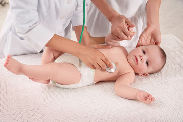 Obraz na płótnie Canvas Doctor examining baby with stethoscope at home