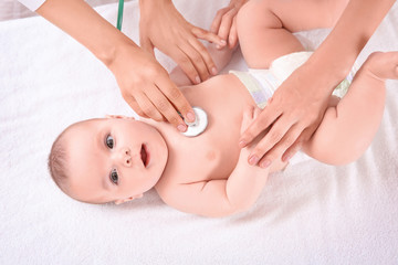 Fototapeta na wymiar Doctor examining baby with stethoscope at home