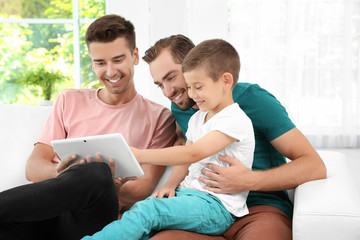 Male gay couple with foster son resting at home. Adoption concept