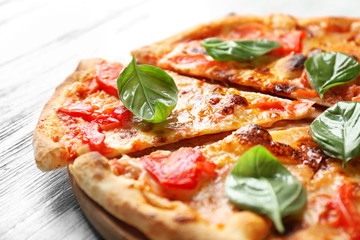 Delicious pizza with tomatoes and fresh basil on wooden background