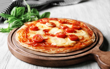 Delicious pizza and fresh basil on kitchen table
