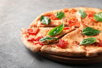 Delicious pizza with tomatoes and fresh basil on grey background
