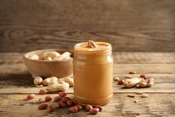 Glass jar with creamy peanut butter on kitchen table