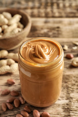Glass jar with creamy peanut butter on kitchen table